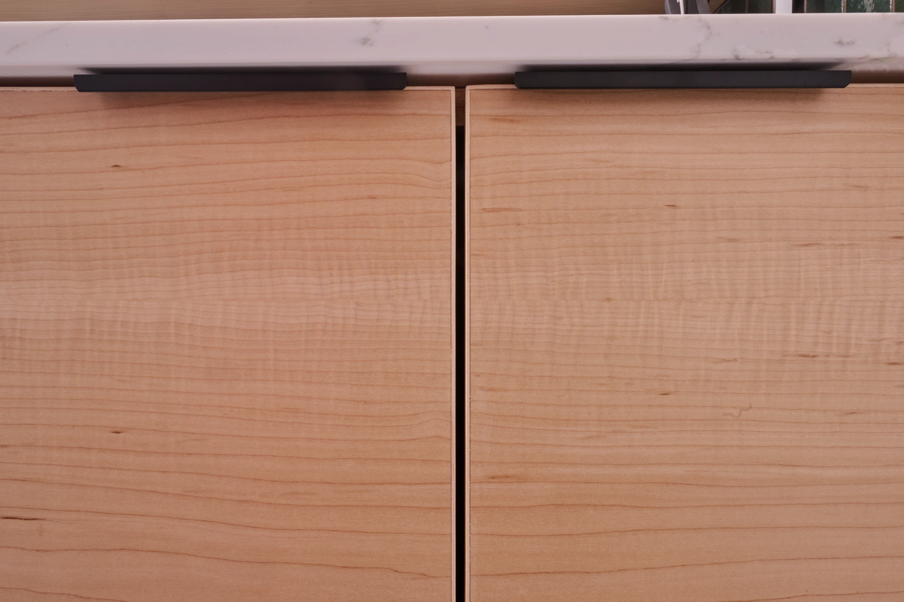 Two maple drawer fronts close up, showing the figured grain and black edge pulls.
