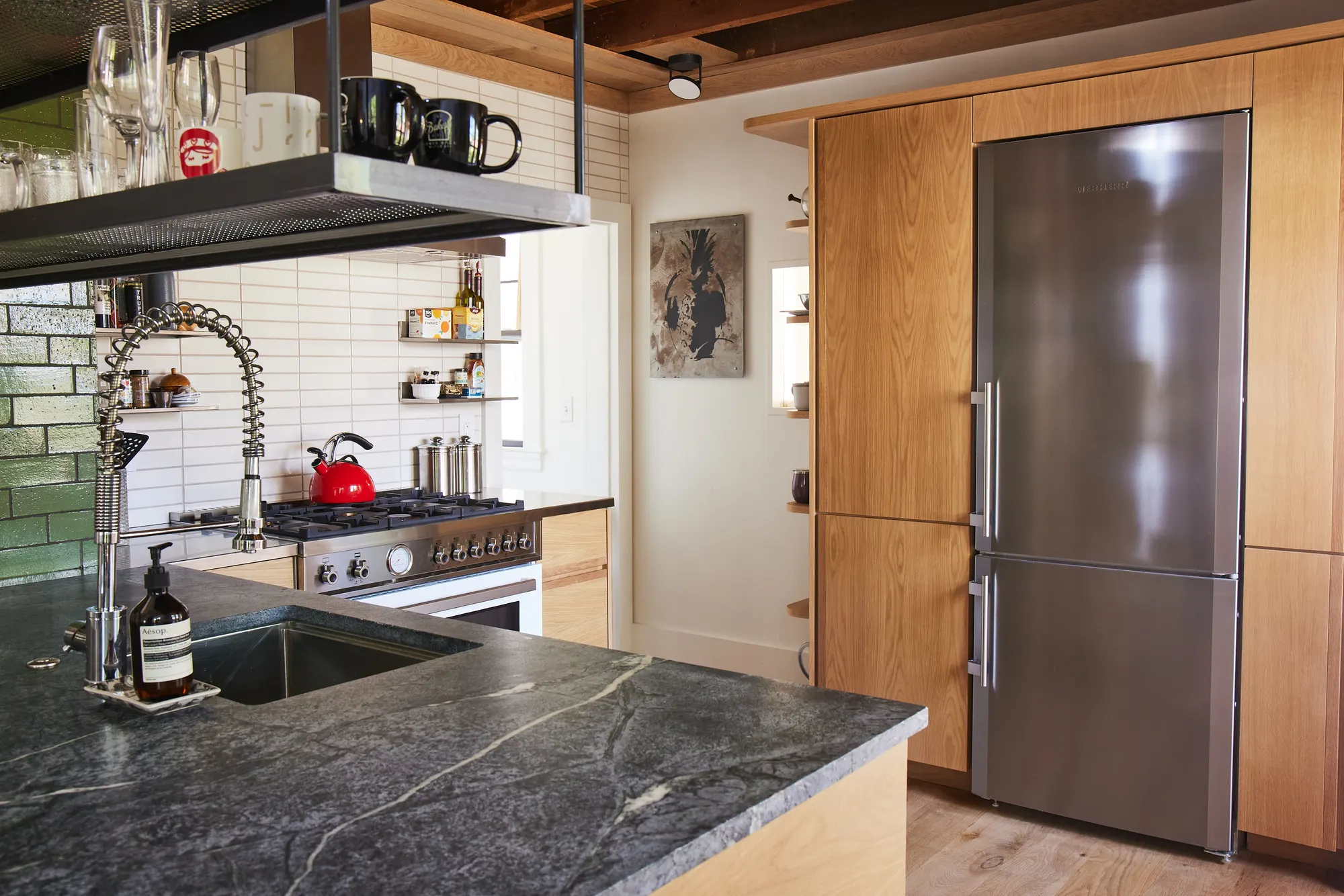 A soapstone counter and a steel fridge set into timber cabinets, with the range beyond.