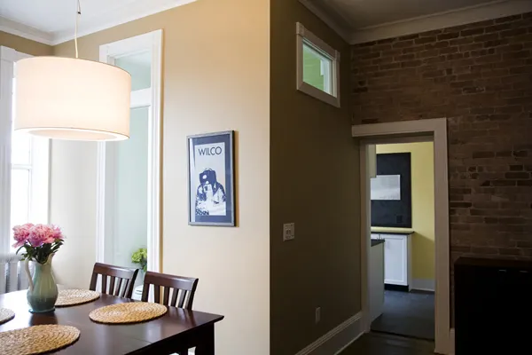 The dining table and a doorway through a brick wall to the kitchen.